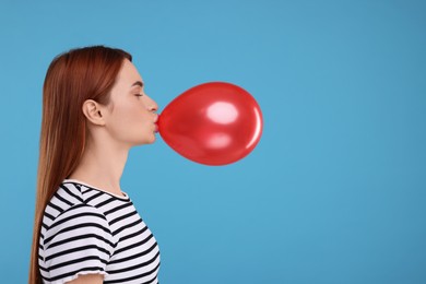 Woman inflating red balloon on light blue background, space for text