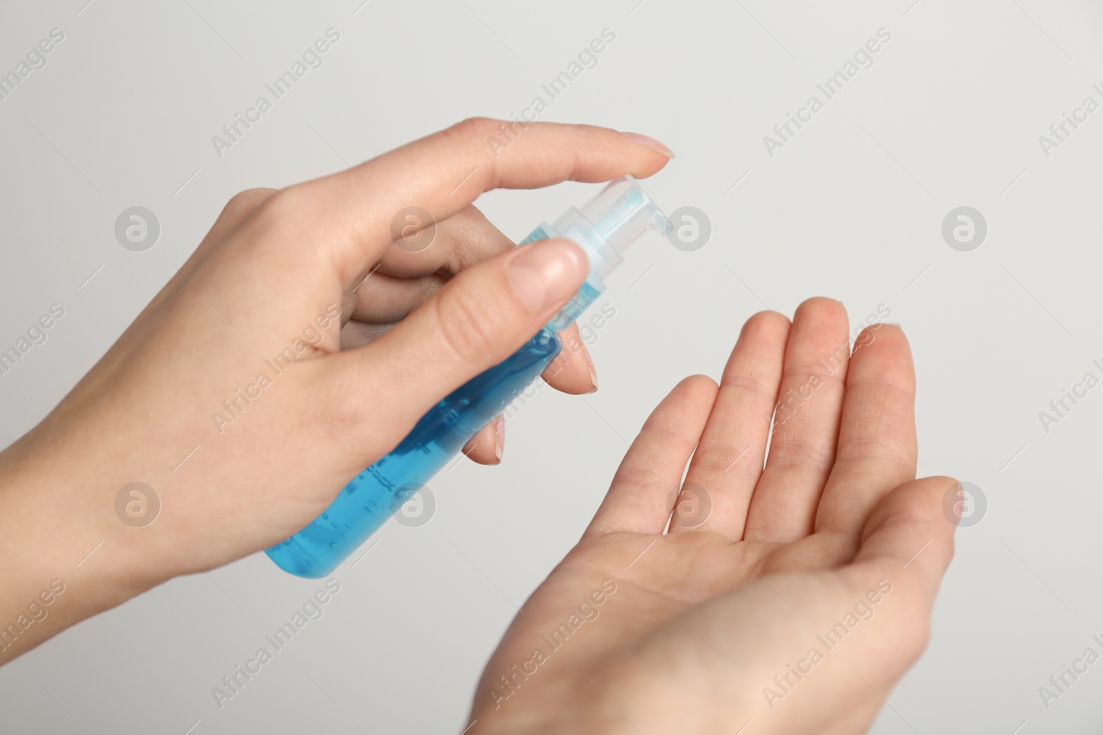 Photo of Woman applying antiseptic gel on light grey background, closeup