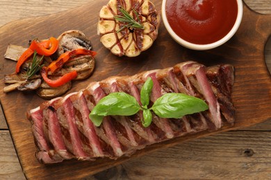 Photo of Delicious grilled beef steak with spices and tomato sauce on wooden table, top view