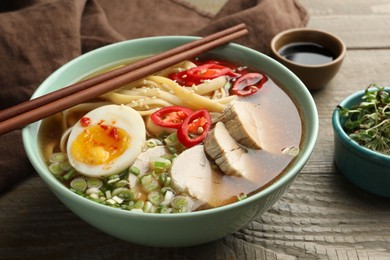 Delicious ramen in bowl on wooden table, closeup. Noodle soup