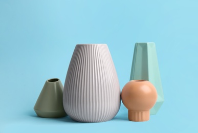Photo of Stylish empty ceramic vases on light blue background