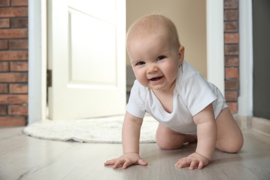 Photo of Cute little baby crawling on floor indoors, space for text