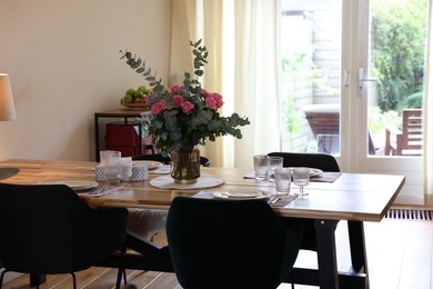 Photo of Stylish dining room with comfortable furniture, big window and bouquet of roses