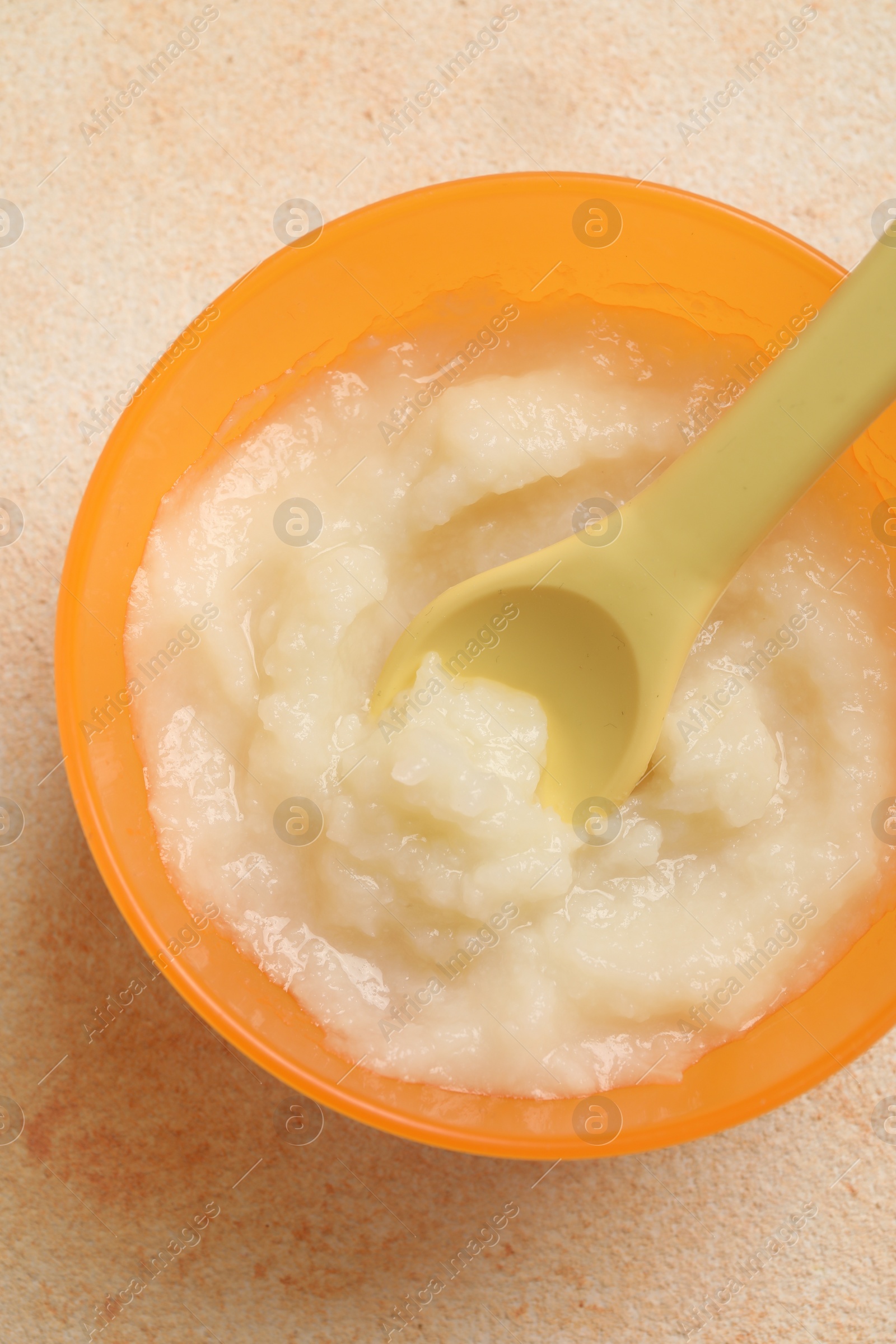 Photo of Baby food. Bowl with cauliflower puree on beige textured table, top view