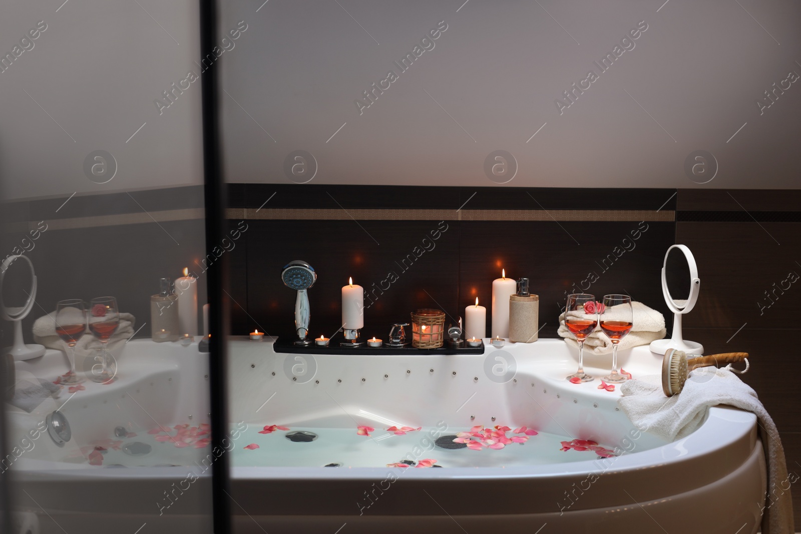 Photo of Bathtub with glasses of wine and candles indoors. Romantic atmosphere