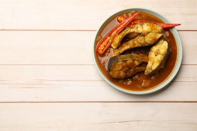 Photo of Tasty fish curry on white wooden table, top view. Space for text. Indian cuisine