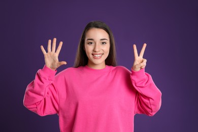 Photo of Woman showing number seven with her hands on purple background