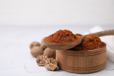 Photo of Bowl and spoon with nutmeg powder on white table. Space for text