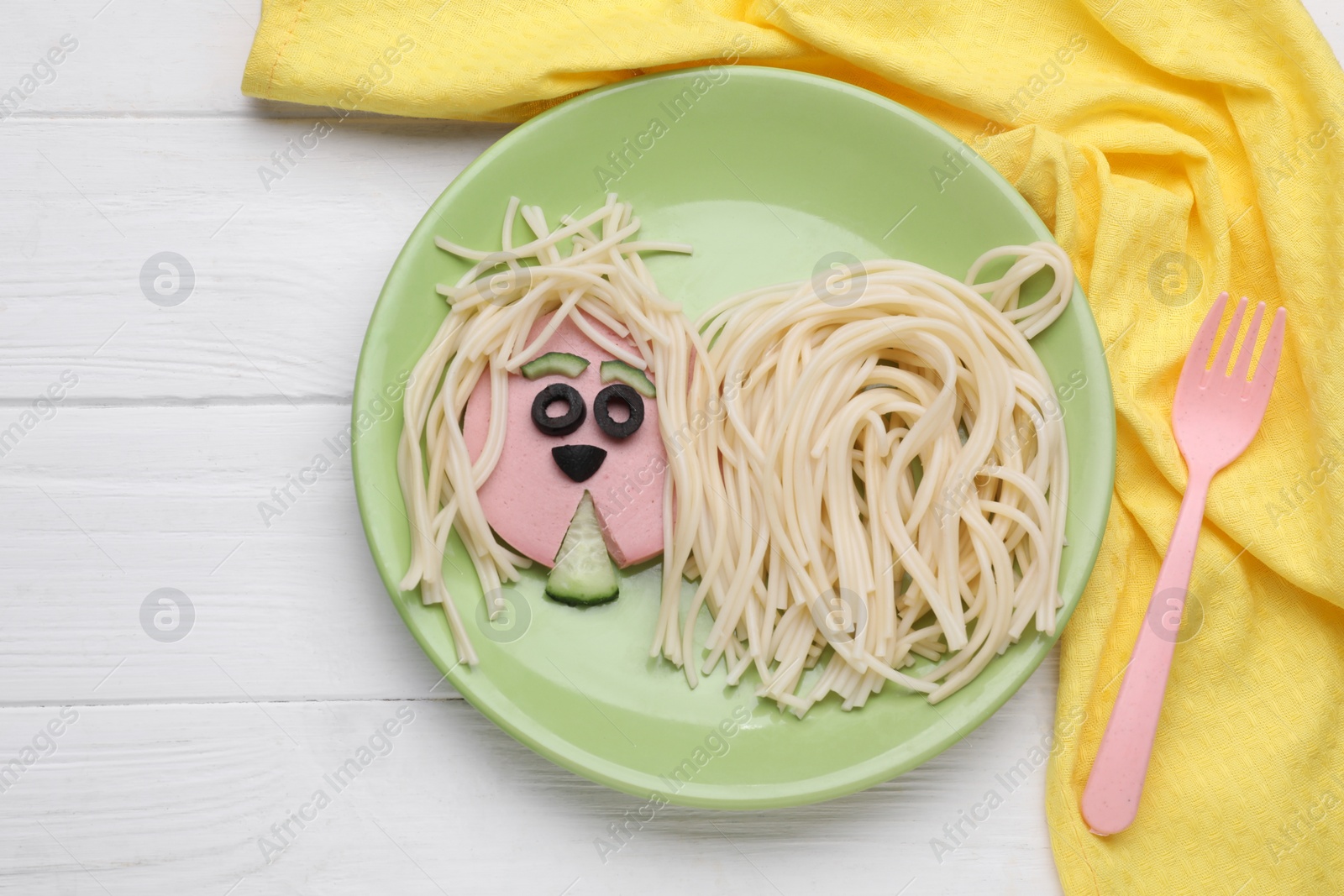 Photo of Creative serving for kids. Plate with cute dog made of tasty pasta, sausage and cucumber on white wooden table, flat lay. Space for text