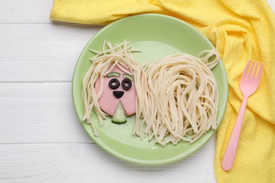 Photo of Creative serving for kids. Plate with cute dog made of tasty pasta, sausage and cucumber on white wooden table, flat lay. Space for text