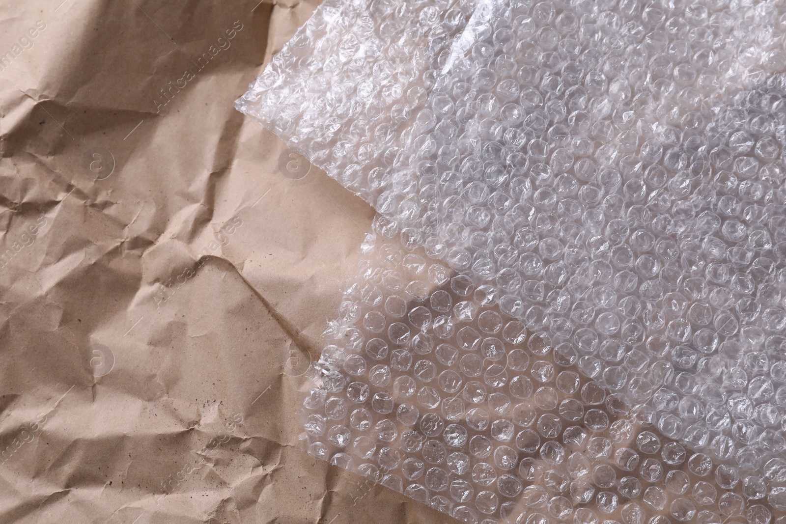 Photo of Transparent bubble wrap on kraft paper, top view. Space for text