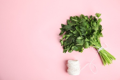 Photo of Bunch of fresh green parsley and twine on color background, flat lay. Space for text