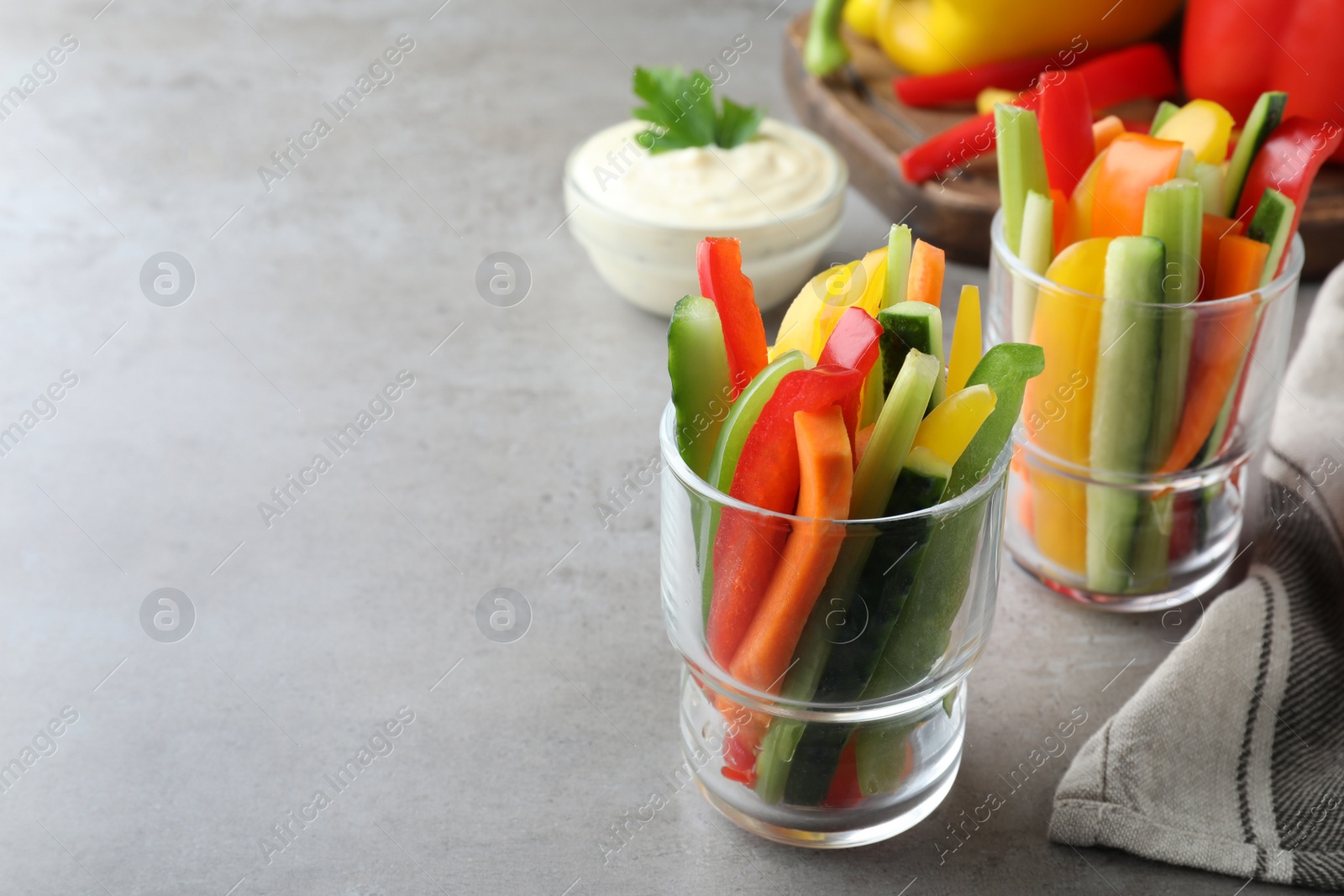 Photo of Different vegetables cut in sticks on light grey table. Space for text