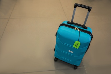 Photo of Suitcase with TRAVEL INSURANCE label indoors. Space for text