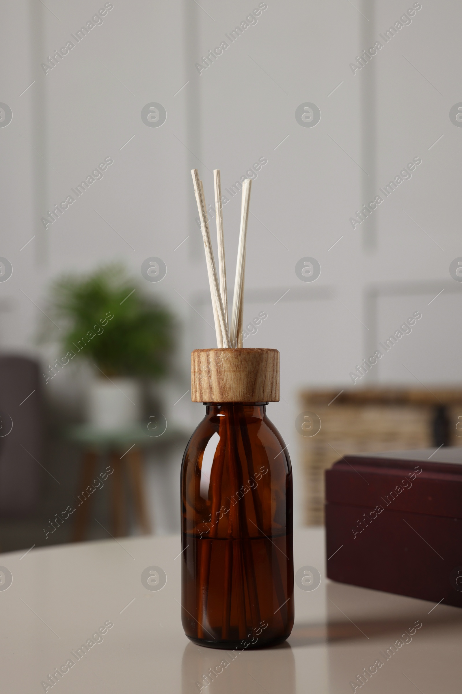 Photo of Aromatic reed air freshener and wooden box on light table indoors