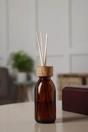 Aromatic reed air freshener and wooden box on light table indoors