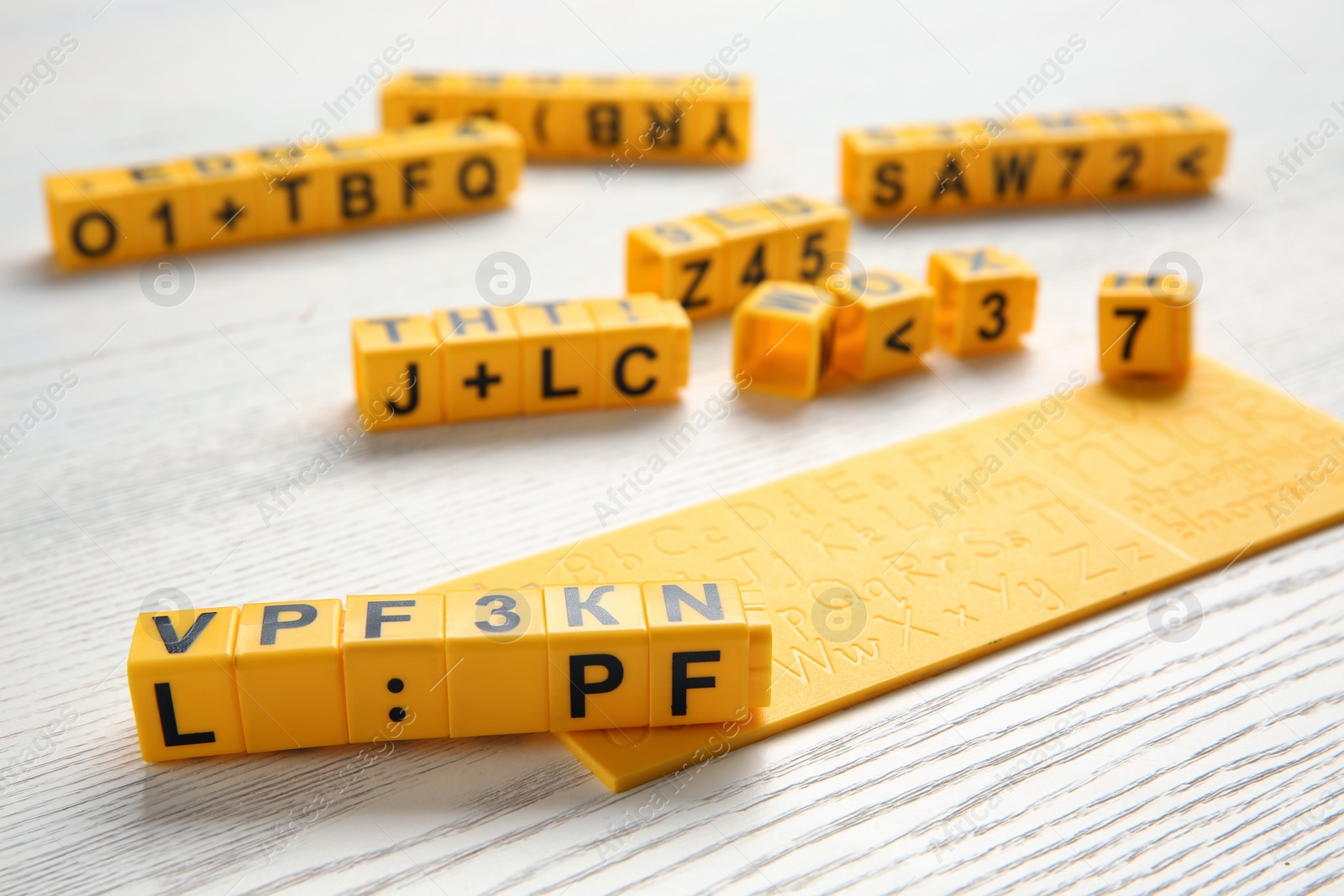 Photo of Yellow cubes with letters and symbols on white wooden table