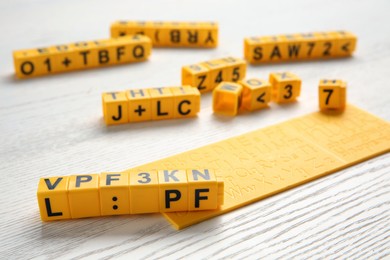 Photo of Yellow cubes with letters and symbols on white wooden table