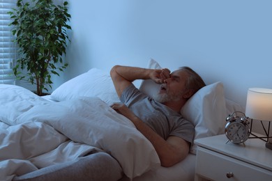 Sleepy senior man in bed at home