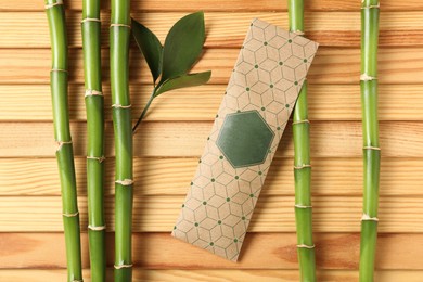 Photo of Scented sachet and bamboo branches on wooden table, flat lay