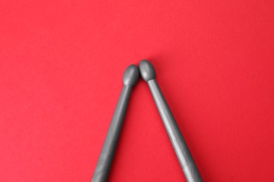 Photo of Two gray drum sticks on red background, top view