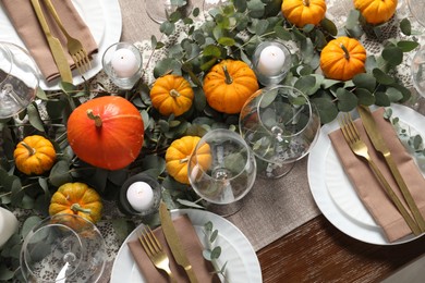 Beautiful autumn table setting. Plates, cutlery, glasses, pumpkins and floral decor, above view