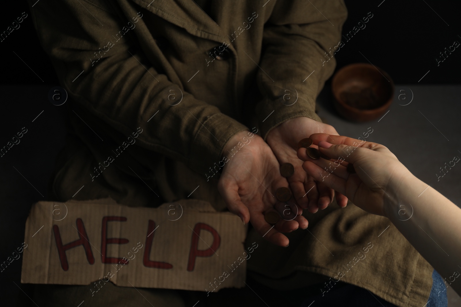 Photo of Woman giving coins to homeless with help sign, closeup. Charity and donation