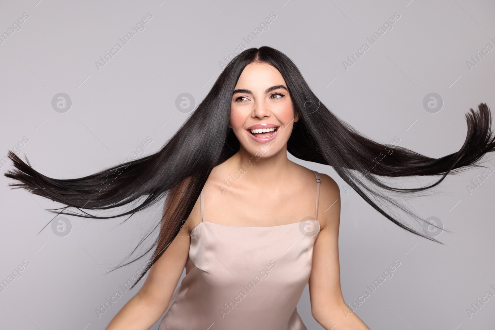 Photo of Portrait of beautiful young woman with healthy strong hair on light grey background