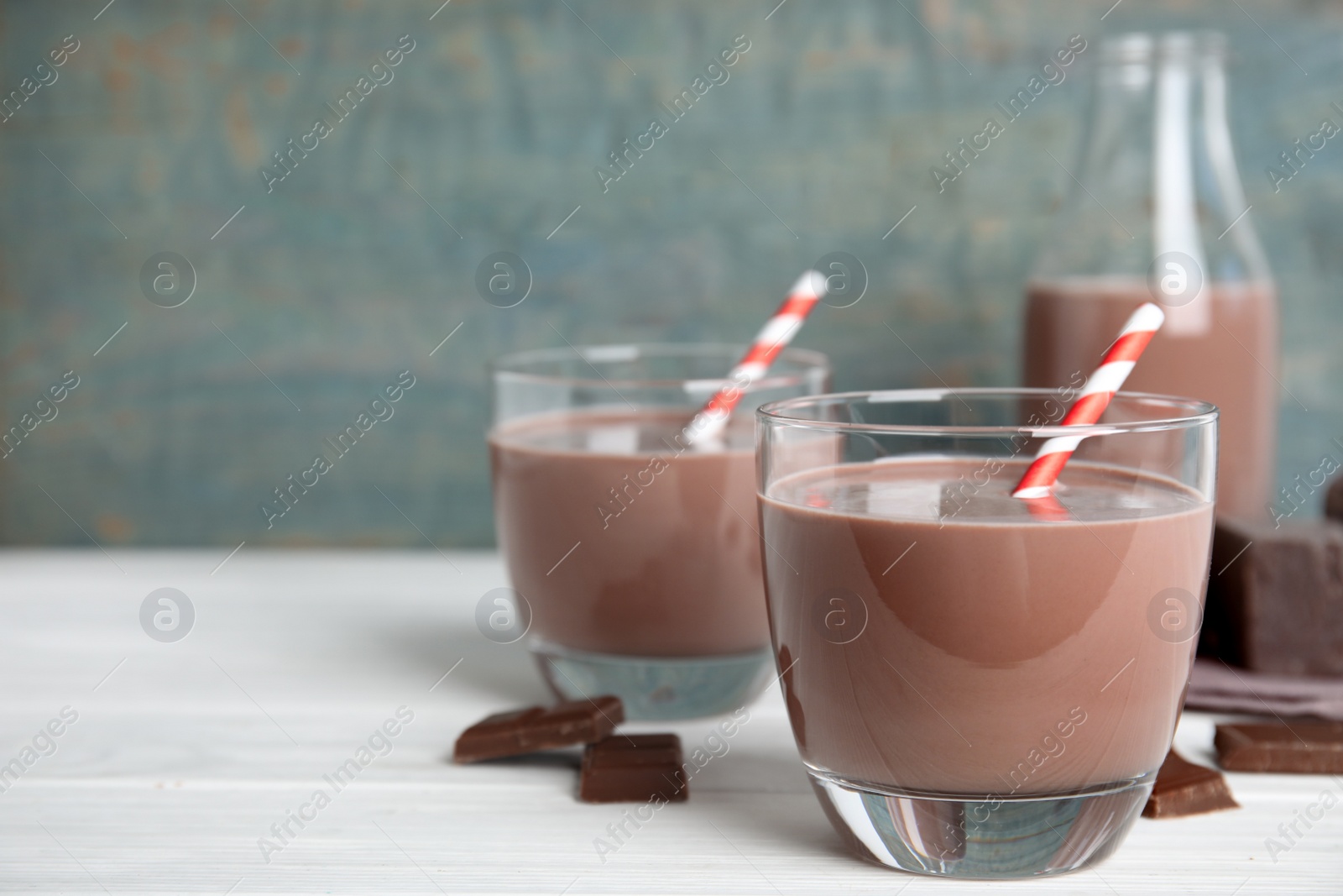 Photo of Delicious chocolate milk on white wooden table. Space for text