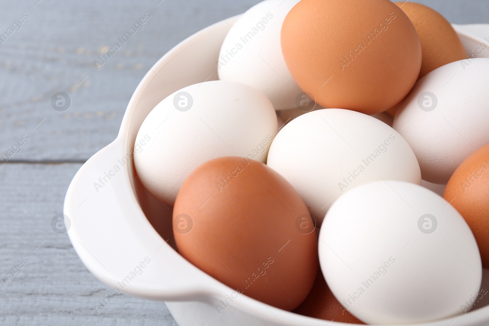 Photo of Unpeeled boiled eggs in saucepan on grey wooden table, closeup