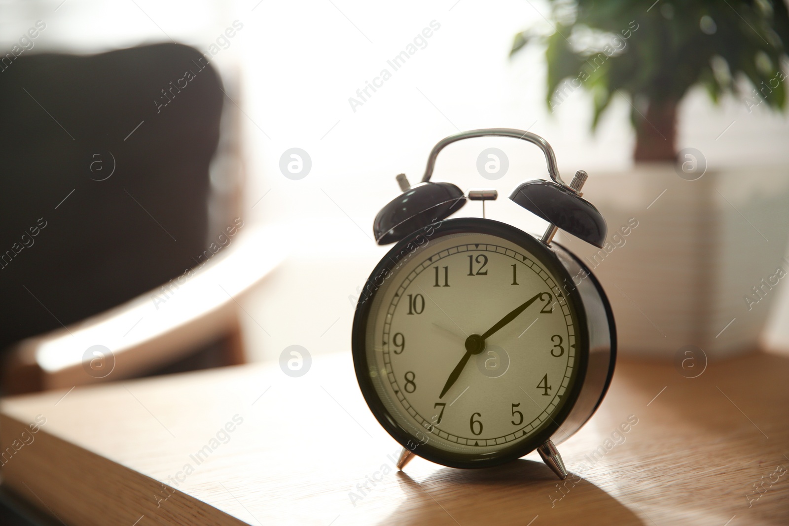 Photo of Alarm clock on wooden table at home. Morning time