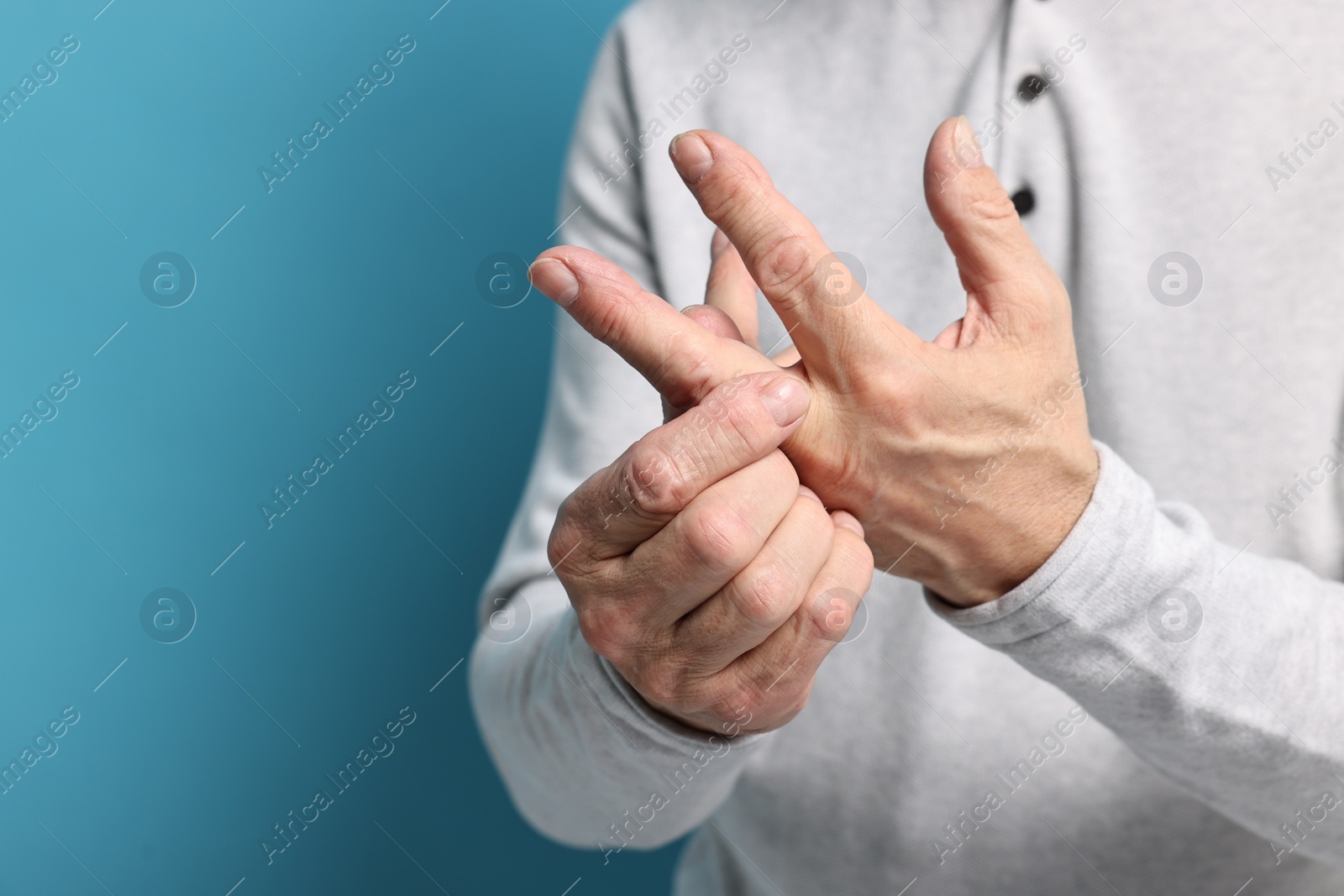 Photo of Arthritis symptoms. Man suffering from pain in hand on light blue background, closeup. Space for text