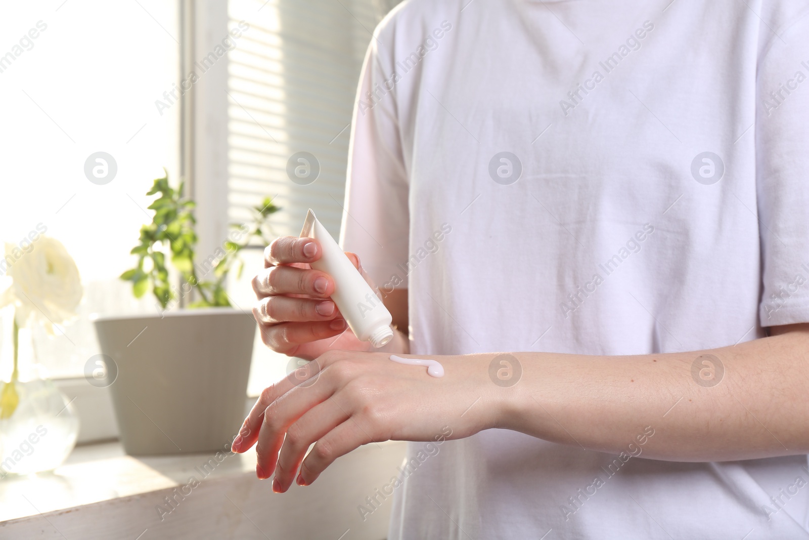 Photo of Woman applying hand cream at home, closeup