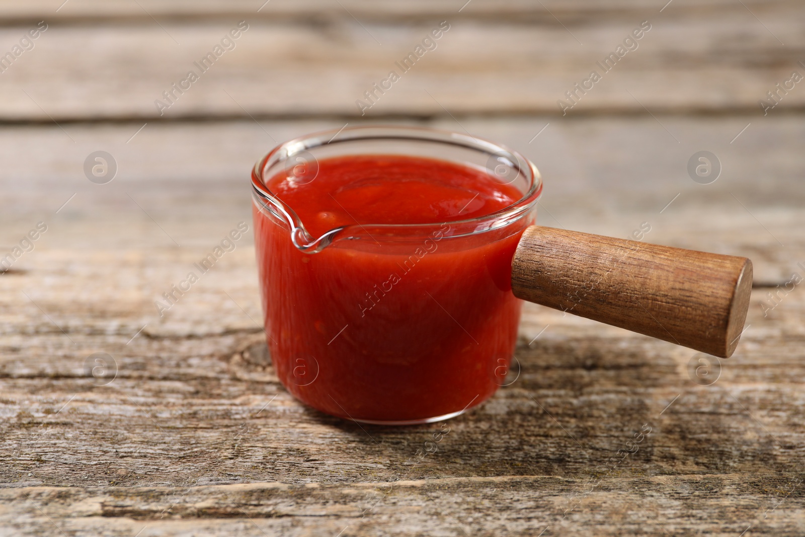 Photo of Delicious ketchup on wooden table, closeup. Tomato sauce