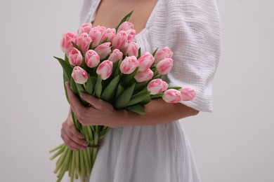 Photo of Woman with bouquet of beautiful fresh tulips on light grey background, closeup