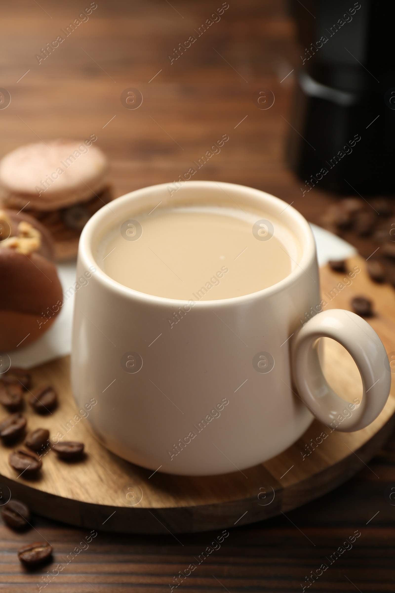 Photo of Cup of coffee and delicious macarons on wooden table, closeup