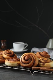 Tasty cinnamon rolls on black table, space for text