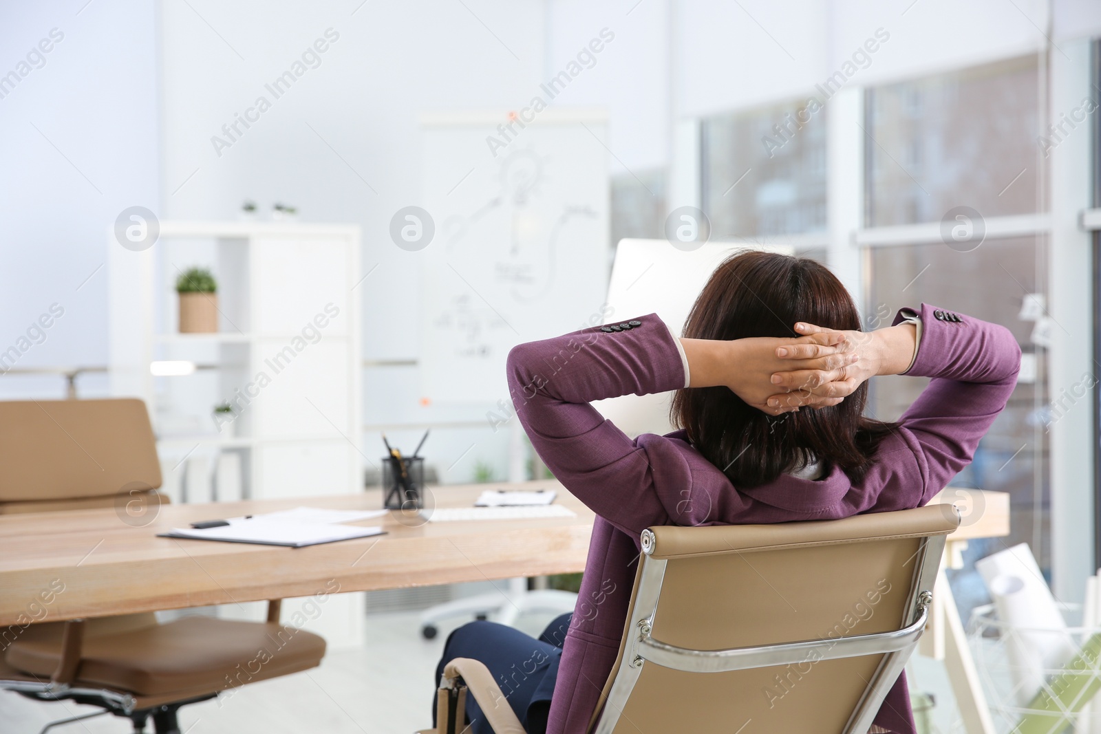 Photo of Woman relaxing in office chair at workplace, back view