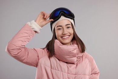 Photo of Winter sports. Happy woman with snowboard goggles on grey background