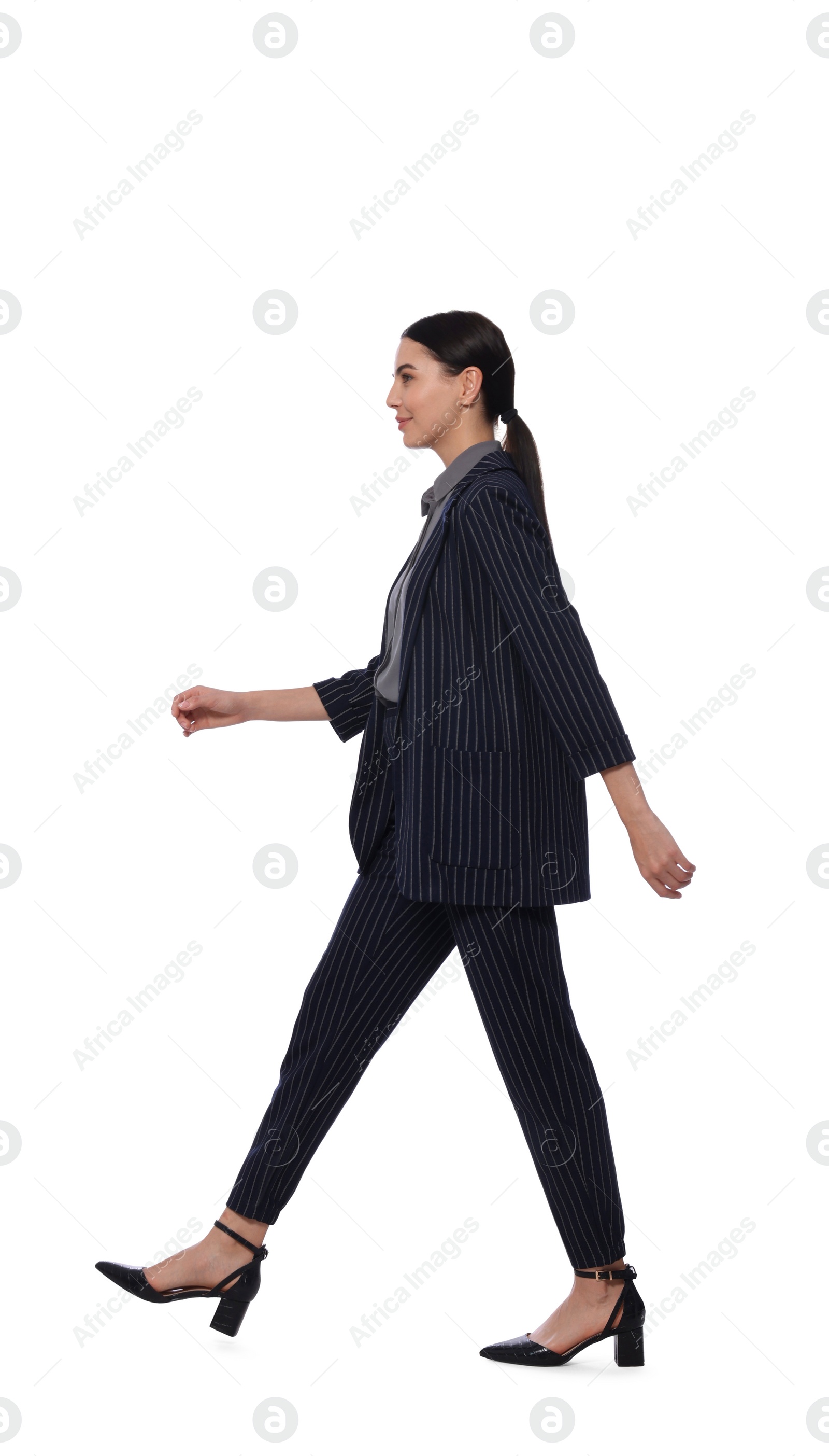 Photo of Young woman in formal suit walking on white background