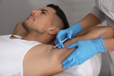 Photo of Cosmetologist injecting man's armpit in clinic. Treatment of hyperhidrosis