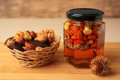 Different nuts with honey in jar and wicker basket with snacks on wooden table