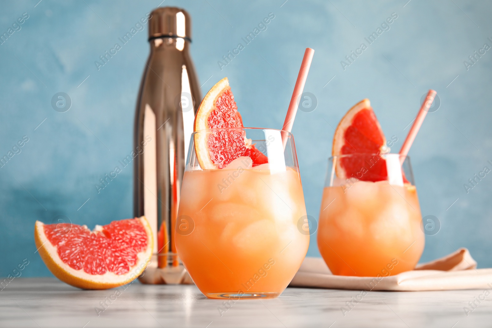 Photo of Glasses of grapefruit cocktails served on table against color background