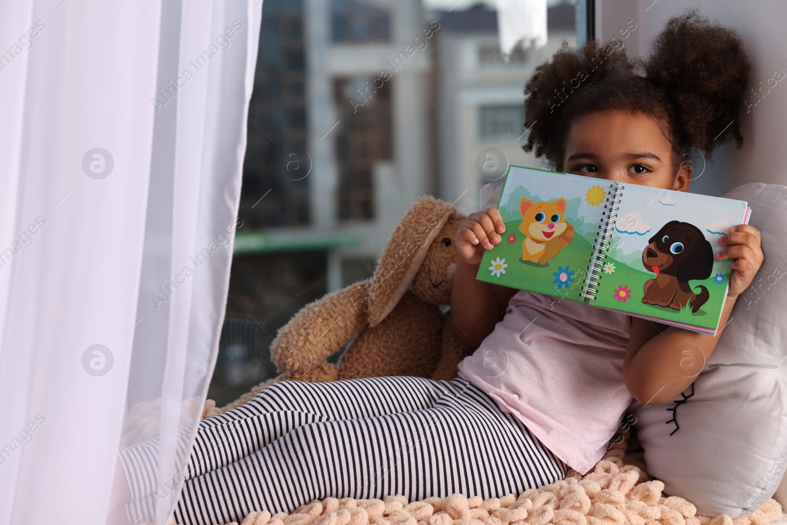 Photo of African American girl with book at home