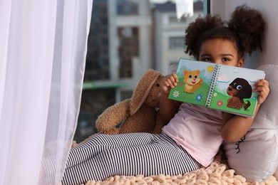 Photo of African American girl with book at home