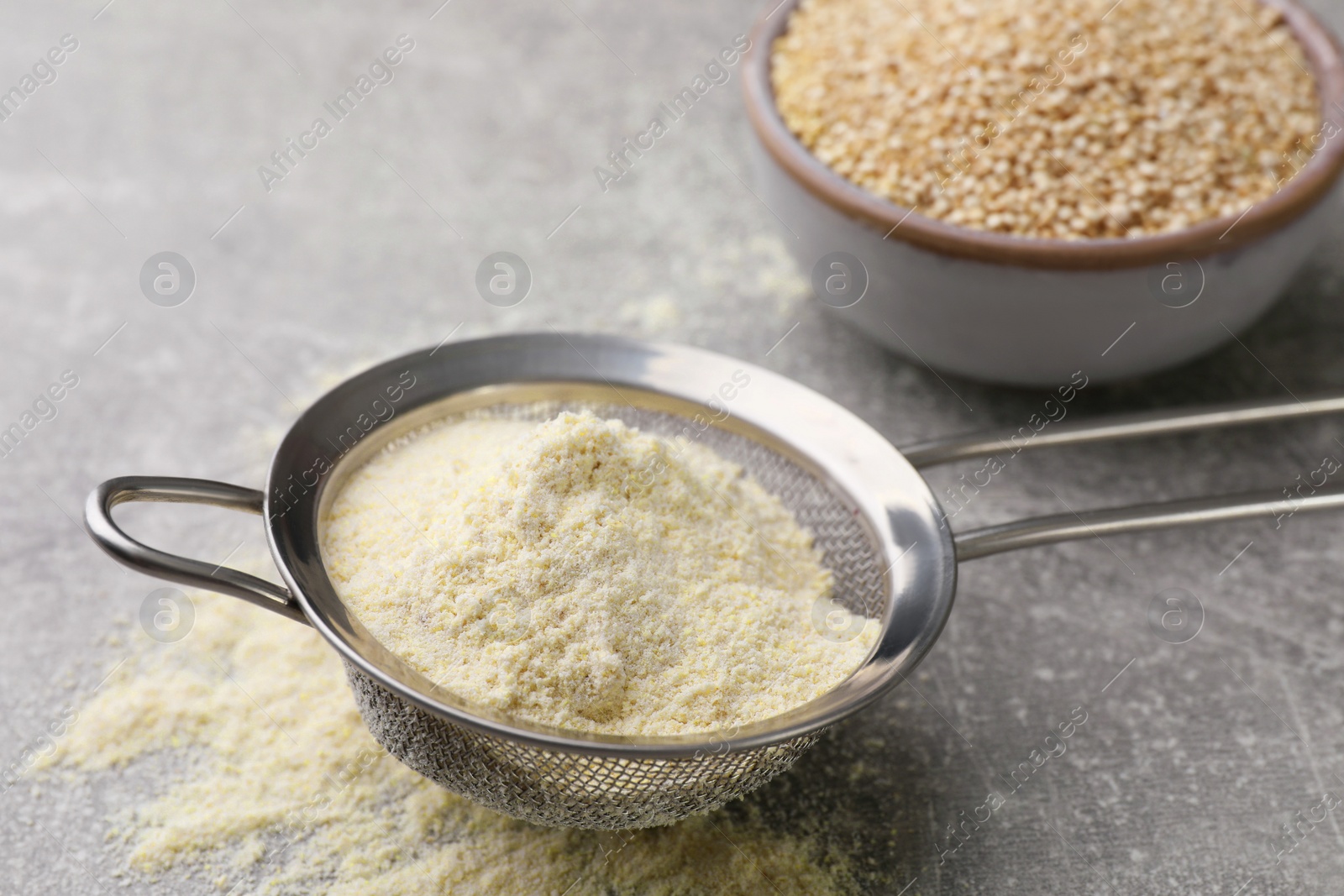 Photo of Sieve with quinoa flour on light grey table, closeup