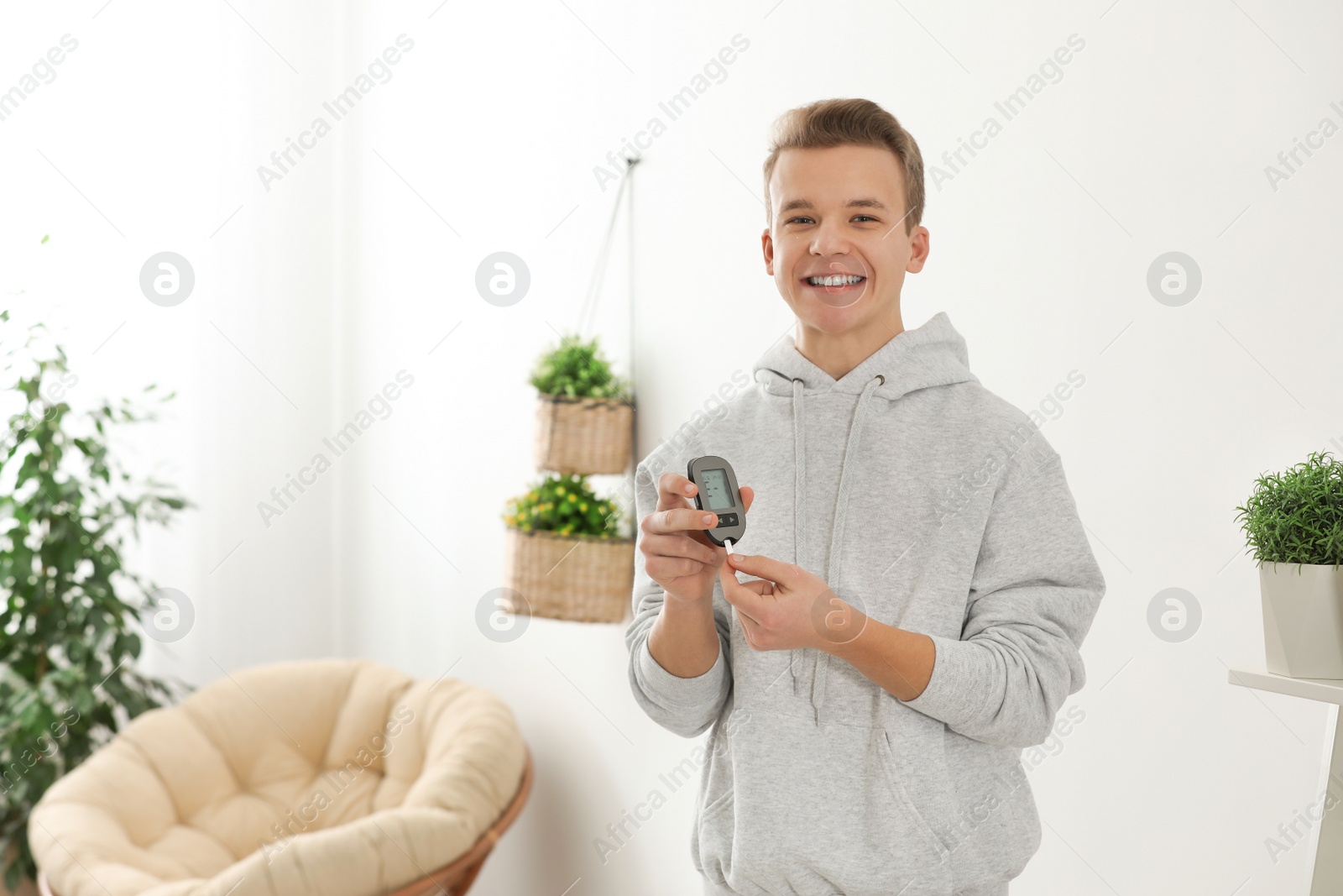 Photo of Teen boy holding digital glucometer at home. Diabetes control