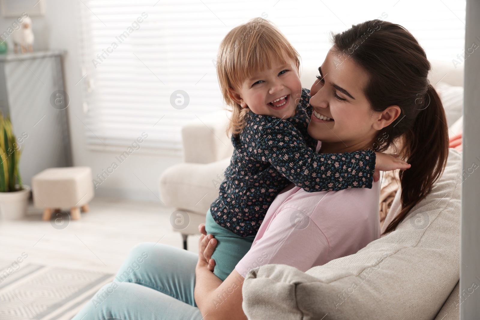 Photo of Mother with her cute little daughter on sofa at home, space for text