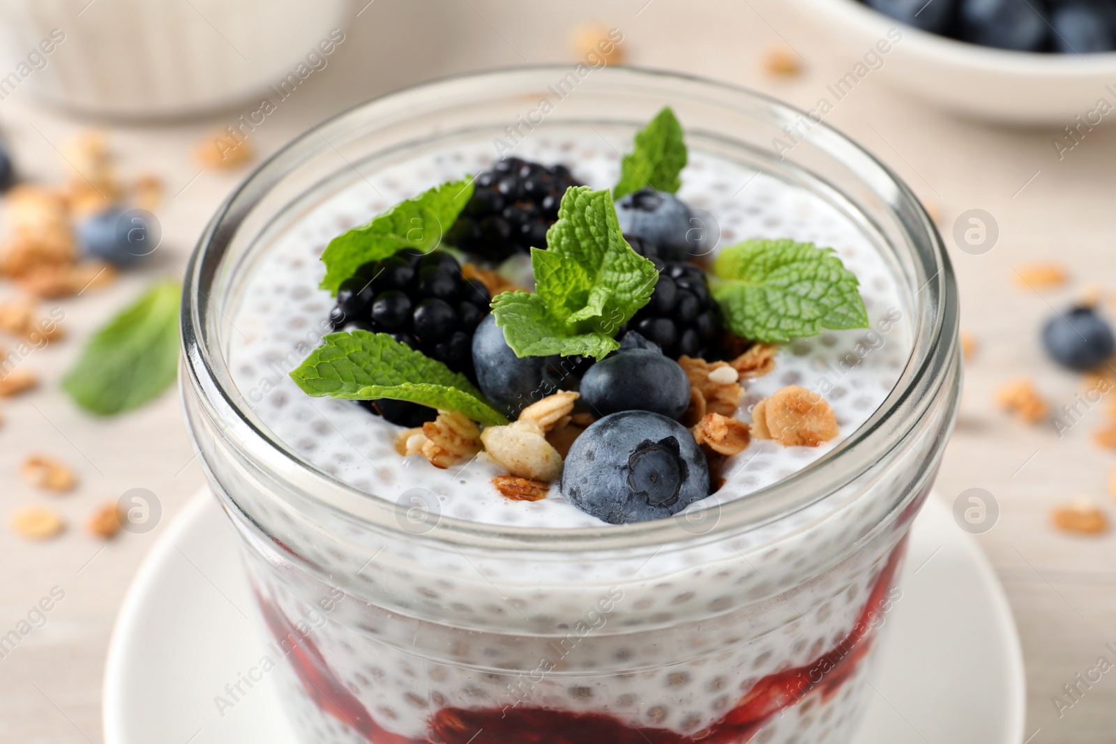 Photo of Delicious chia pudding with berries and granola in jar, closeup