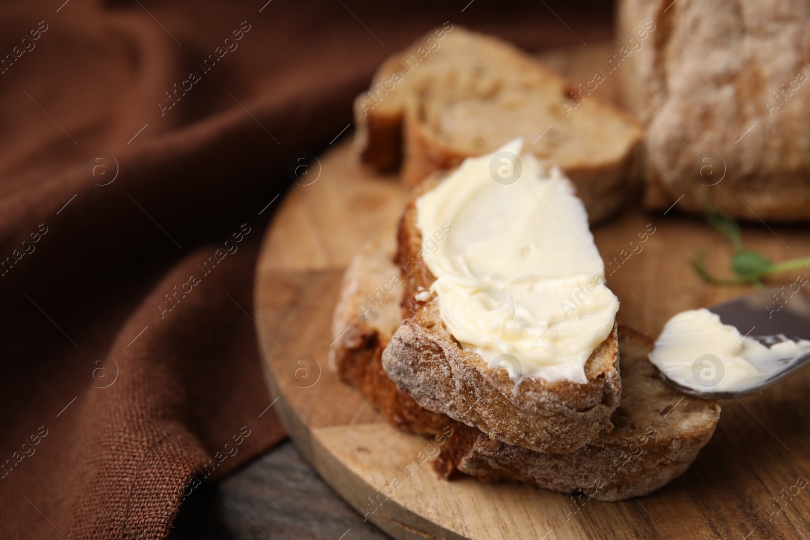 Photo of Slices of tasty bread with butter and knife on wooden table, closeup, Space for text